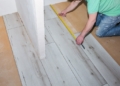 Worker making laminate flooring in apartment. Maintenance repair renovation. Wooden parquet planks indoors.
