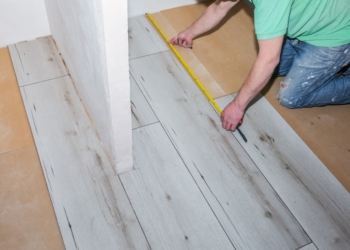 Worker making laminate flooring in apartment. Maintenance repair renovation. Wooden parquet planks indoors.