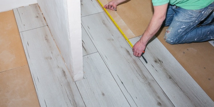 Worker making laminate flooring in apartment. Maintenance repair renovation. Wooden parquet planks indoors.